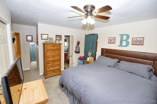 bedroom featuring connected bathroom, ceiling fan, light colored carpet, and a textured ceiling