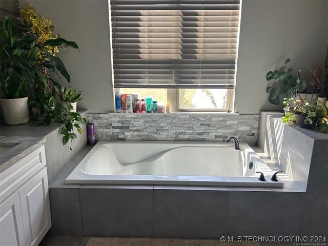 bathroom featuring tiled bath and vanity