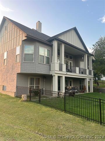 back of house with a lawn and a balcony