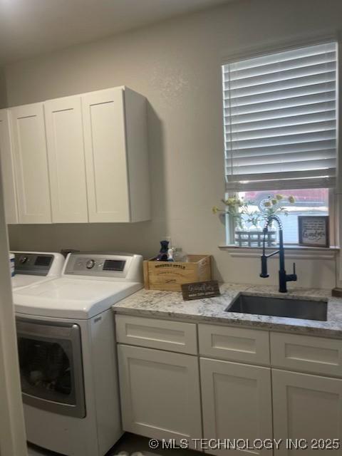 washroom with cabinets, washer and dryer, and sink