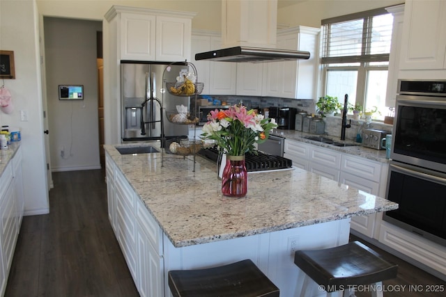 kitchen with white cabinetry, a kitchen bar, stainless steel appliances, range hood, and a kitchen island