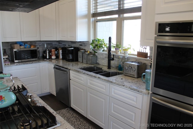 kitchen featuring appliances with stainless steel finishes, backsplash, white cabinetry, and sink