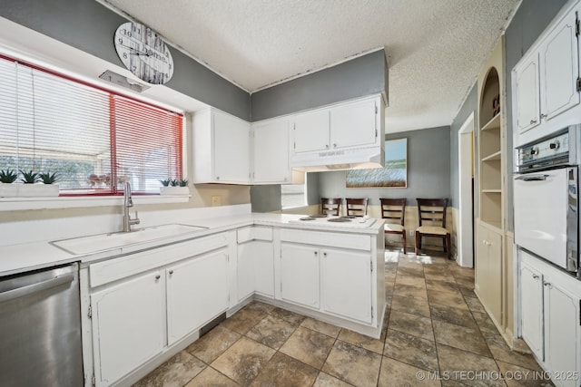 kitchen featuring sink, white appliances, a textured ceiling, white cabinets, and kitchen peninsula