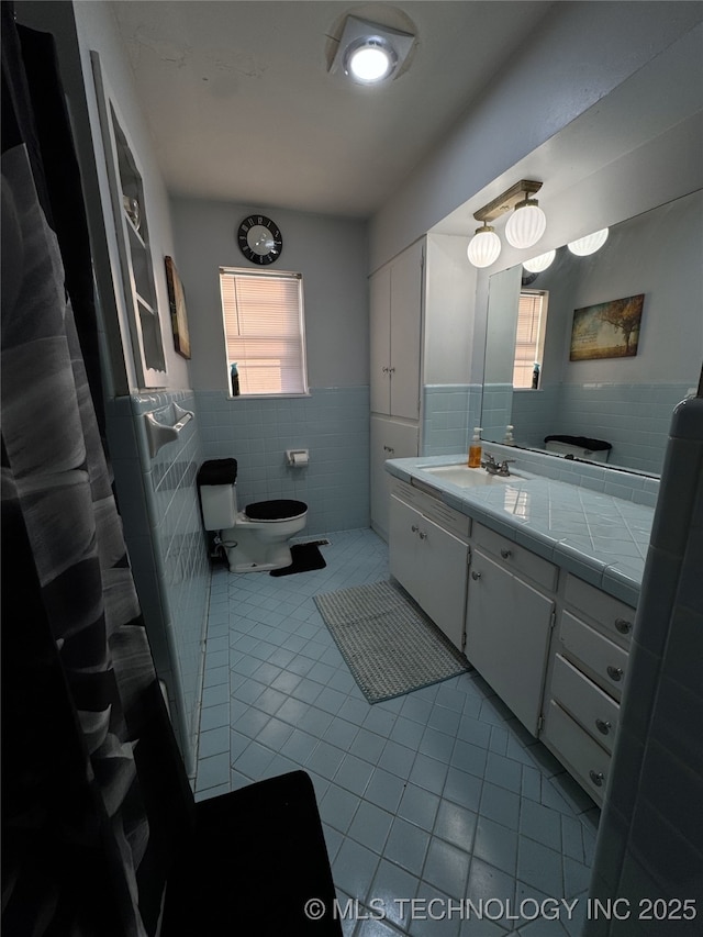 bathroom with tile walls, vanity, and tile patterned flooring