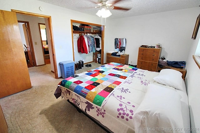 bedroom featuring ceiling fan, a closet, light colored carpet, and a textured ceiling