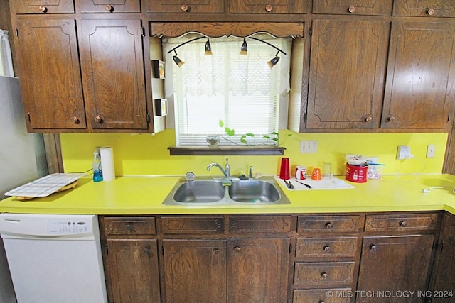 kitchen featuring white dishwasher, dark brown cabinetry, and sink