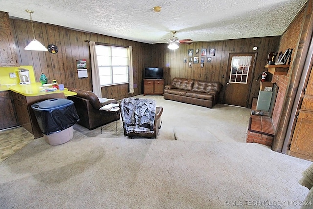 carpeted living room featuring a textured ceiling, ceiling fan, and wood walls