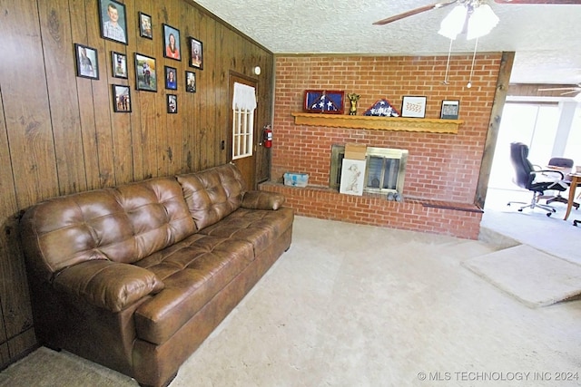 living room with wood walls, light carpet, ceiling fan, a fireplace, and a textured ceiling