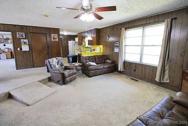 carpeted living room with ceiling fan, a textured ceiling, and wooden walls