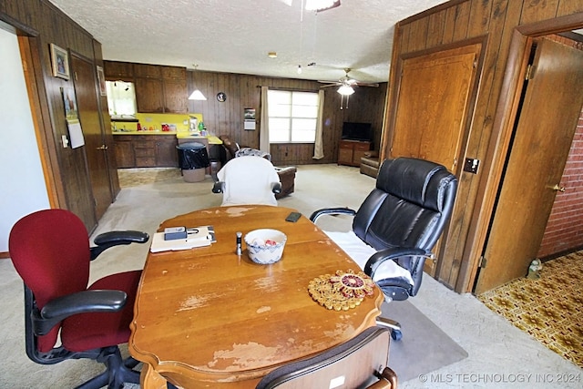 dining area featuring a textured ceiling, ceiling fan, and wood walls