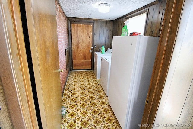 washroom with independent washer and dryer, a textured ceiling, and wooden walls