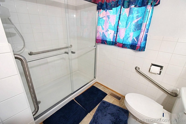 bathroom featuring an enclosed shower, tile patterned floors, tile walls, and toilet