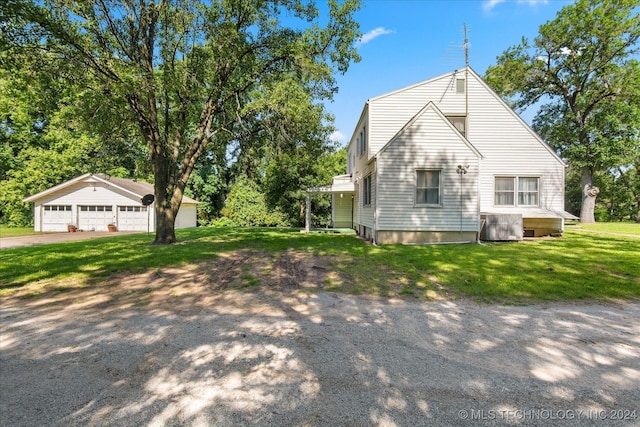 view of side of property featuring a yard, central air condition unit, an outbuilding, and a garage