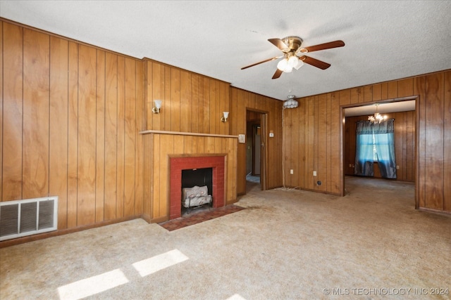 unfurnished living room with a fireplace, light carpet, ceiling fan with notable chandelier, and wood walls