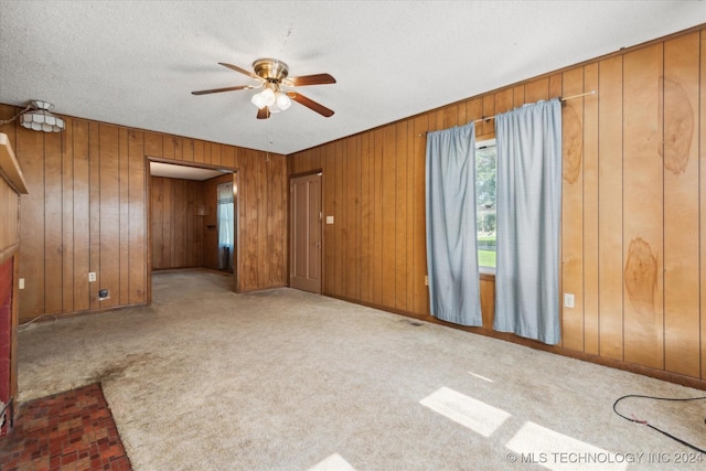 carpeted empty room featuring ceiling fan and wood walls