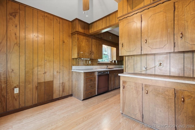 kitchen featuring dishwasher, wood walls, sink, ceiling fan, and light wood-type flooring