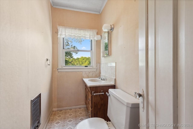 bathroom featuring heating unit, vanity, ornamental molding, and toilet