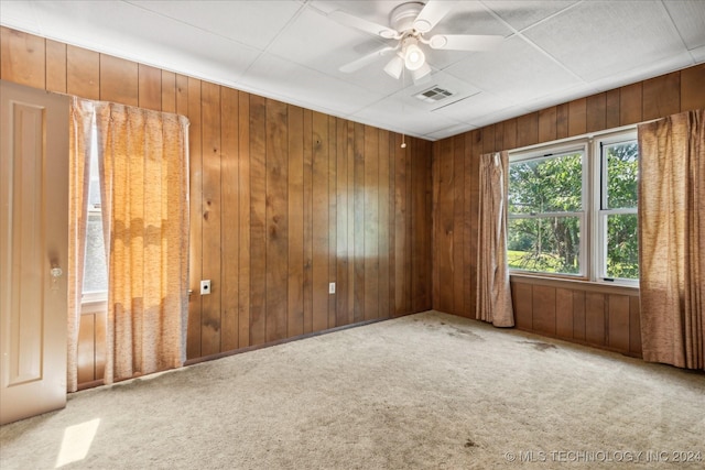 unfurnished room featuring ceiling fan, wooden walls, and carpet floors