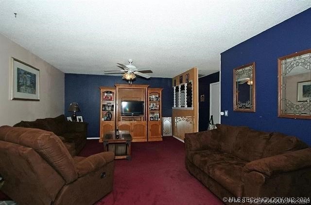 carpeted living room featuring ceiling fan and a textured ceiling