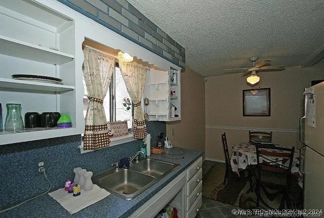 kitchen featuring ceiling fan, sink, and a textured ceiling