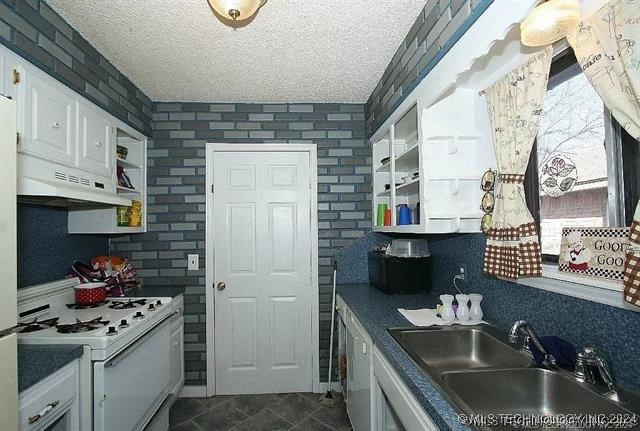 kitchen with white cabinets, a textured ceiling, sink, and gas range gas stove