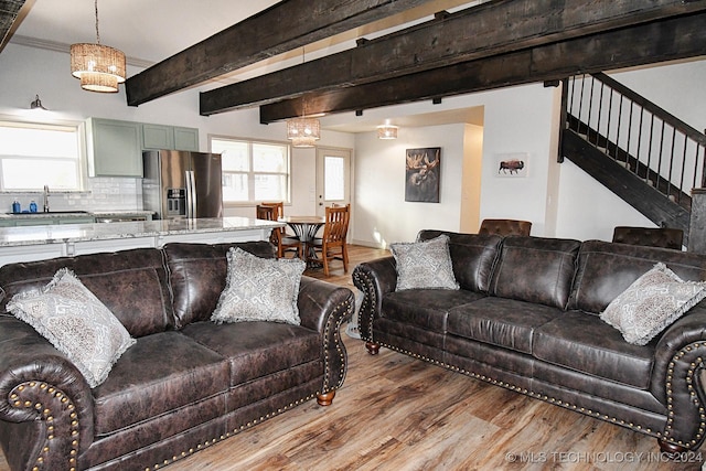 living room with beam ceiling, light hardwood / wood-style floors, and sink