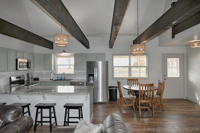 kitchen with hanging light fixtures, gray cabinets, light stone countertops, appliances with stainless steel finishes, and kitchen peninsula