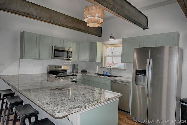 kitchen with kitchen peninsula, stainless steel appliances, sink, decorative light fixtures, and beamed ceiling