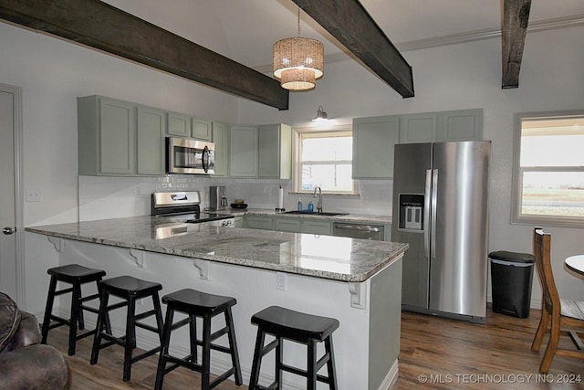 kitchen with kitchen peninsula, appliances with stainless steel finishes, sink, beamed ceiling, and hanging light fixtures