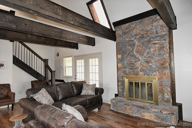 living room featuring hardwood / wood-style floors, beam ceiling, and a stone fireplace