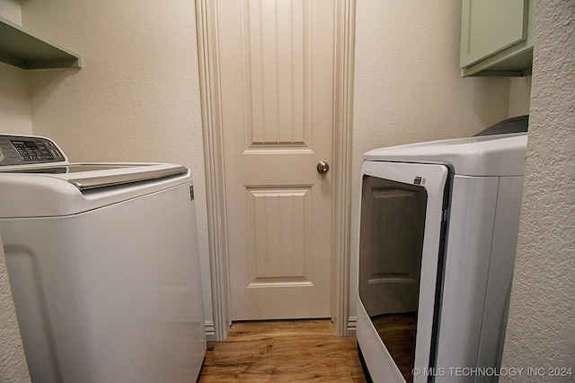 laundry area with washer and dryer, light hardwood / wood-style flooring, and cabinets