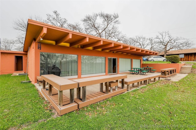 rear view of property featuring a deck and a lawn