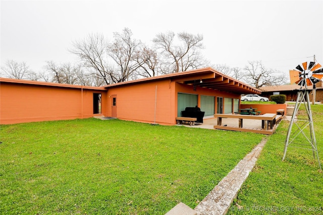 back of property with a yard and a patio