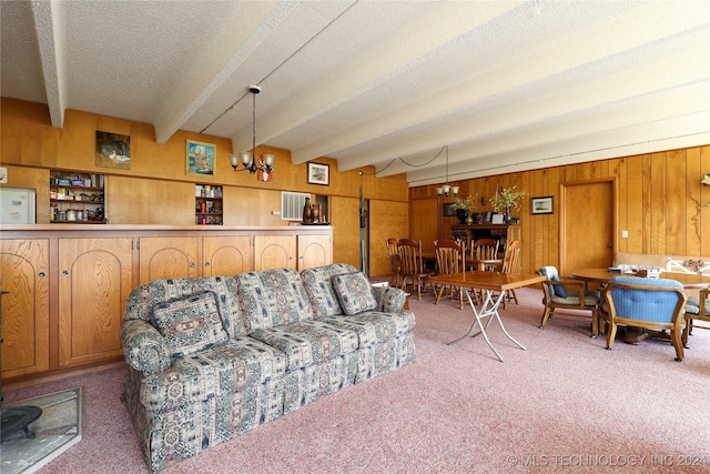 carpeted living room with beamed ceiling, a textured ceiling, a chandelier, and wood walls