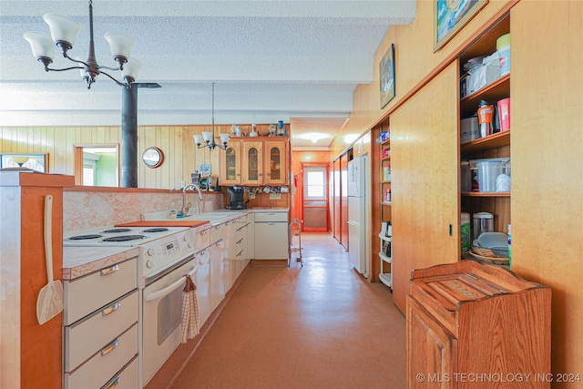 kitchen featuring white appliances, an inviting chandelier, white cabinetry, and hanging light fixtures