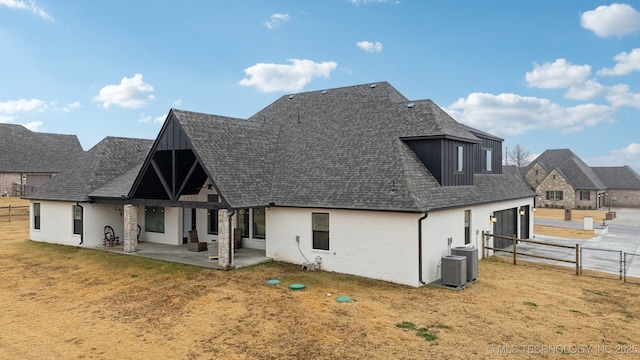 back of property with a patio area, a yard, and roof with shingles