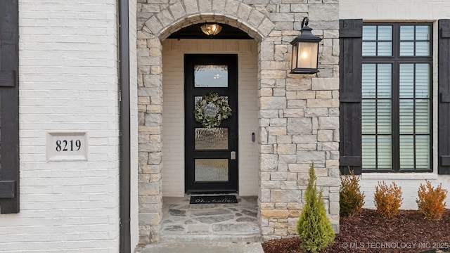 property entrance with stone siding and brick siding