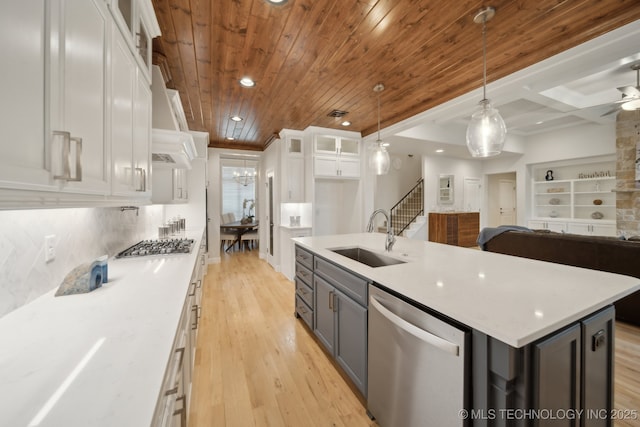 kitchen featuring pendant lighting, stainless steel appliances, open floor plan, a kitchen island with sink, and white cabinetry