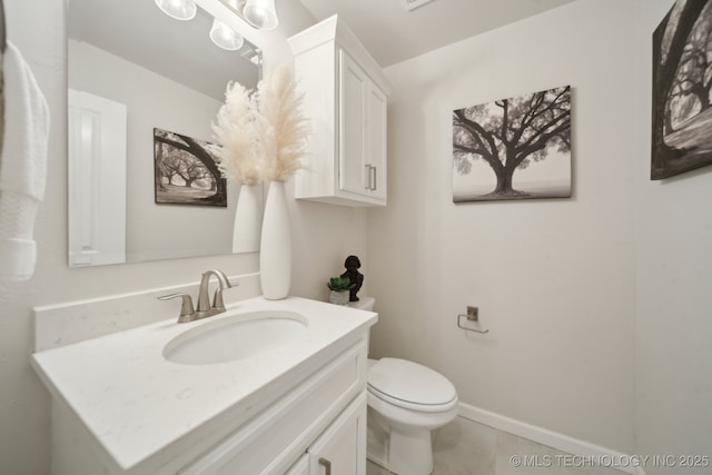 half bathroom with tile patterned flooring, vanity, toilet, and baseboards