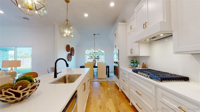 kitchen featuring sink, white cabinets, stainless steel appliances, and decorative light fixtures