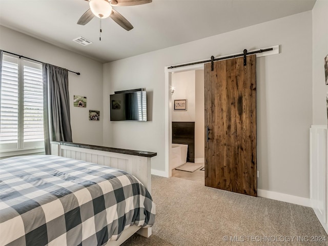 carpeted bedroom featuring a barn door, ensuite bathroom, and ceiling fan