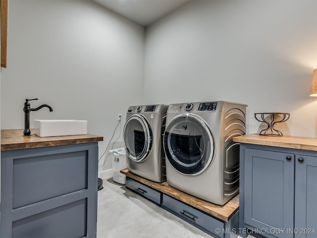 laundry room featuring cabinets, independent washer and dryer, and sink