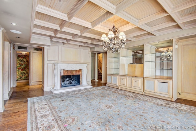 unfurnished living room with ornamental molding, an inviting chandelier, wooden ceiling, a fireplace, and light hardwood / wood-style floors