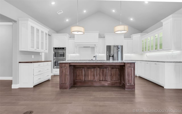 kitchen with pendant lighting, a kitchen island, light stone countertops, and stainless steel appliances