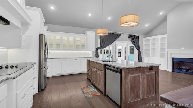 kitchen featuring light stone countertops, a center island with sink, white cabinets, and stainless steel appliances