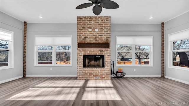 unfurnished living room with a brick fireplace, ceiling fan, ornamental molding, and light hardwood / wood-style flooring