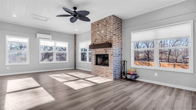 unfurnished living room featuring hardwood / wood-style flooring, a brick fireplace, a wall mounted AC, and ceiling fan