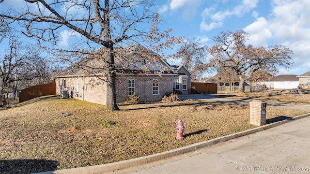 view of front facade with cooling unit and a front lawn