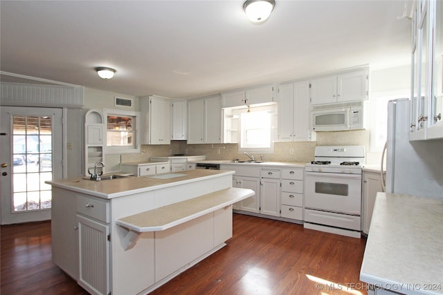 kitchen featuring a wealth of natural light, white appliances, a kitchen island with sink, dark wood-type flooring, and white cabinets