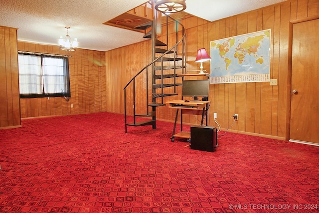 basement featuring carpet flooring, wooden walls, a textured ceiling, and a notable chandelier